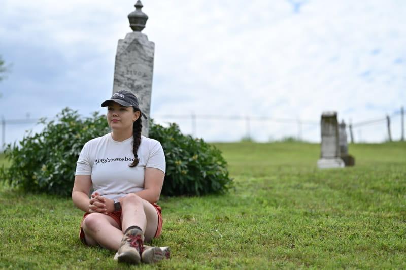 奥布里恩, 部落的通讯主管, 坐在路易莎·布莱恩的墓碑前, 她的第三曾祖母. (小沃尔特·约翰逊摄./美国心脏协会)
